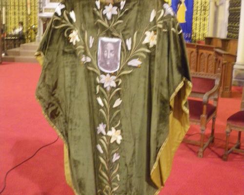 Chasuble avec lys ouverts représentants la fécondité et lys fermés pour les enfants partis trop vite. 
Au centre la Sainte Face