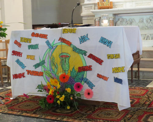Les prénoms des communiants écrits sur la nappe de la table eucharistique