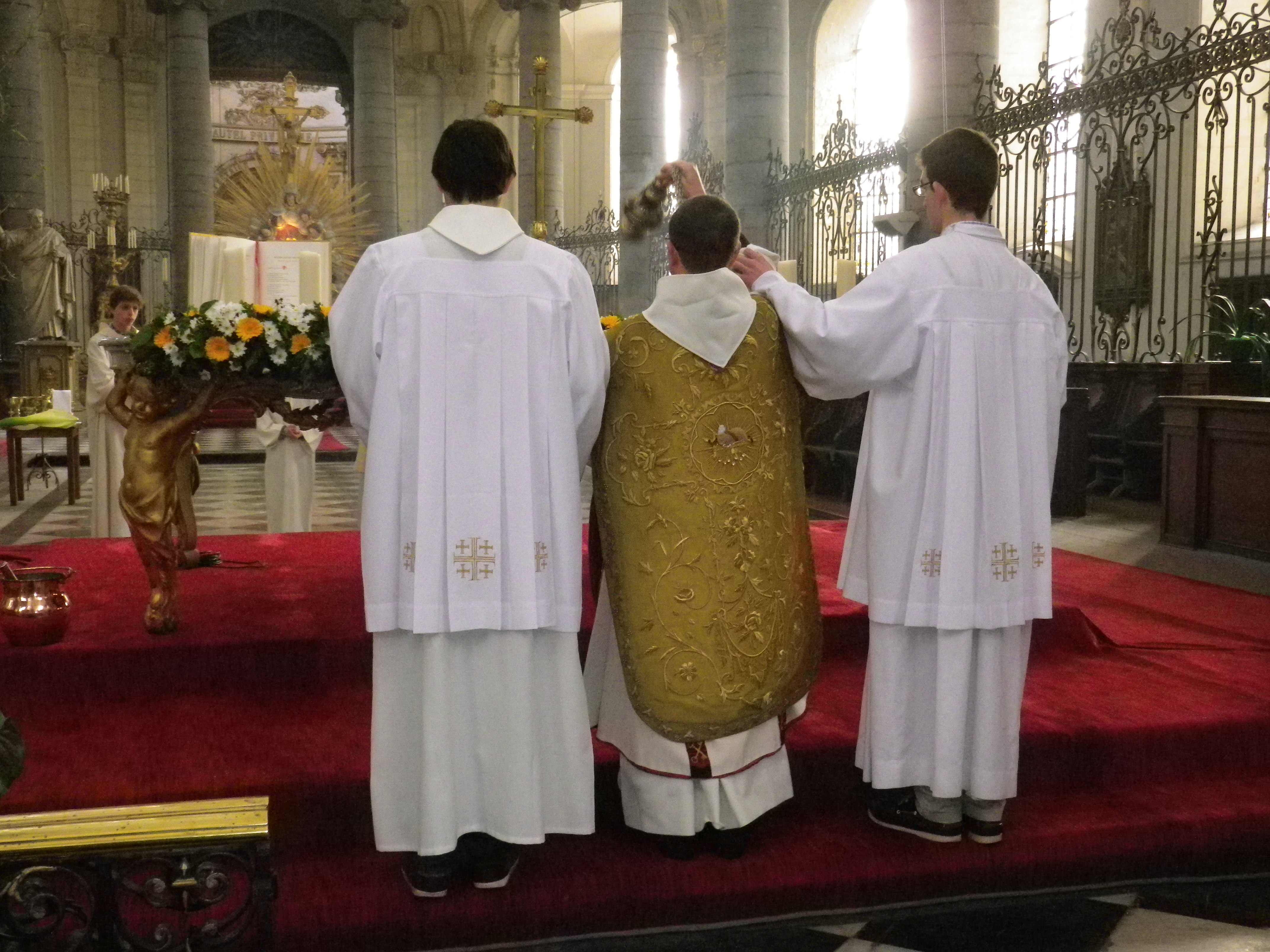 Le père Bernard Descarpentries, qui a revêtu une dalmatique et une superbe chasuble romaine dorée, encense l'autel, entouré des deux cérémoniaires pontificaux: Arnaud et Louis.